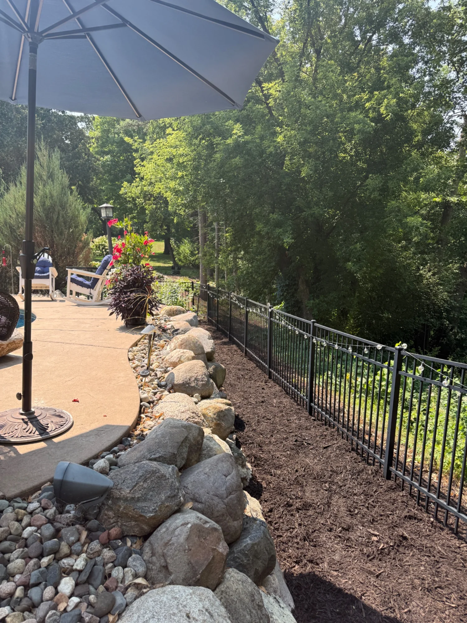 Mulched planting bed along a boulder border beside a patio